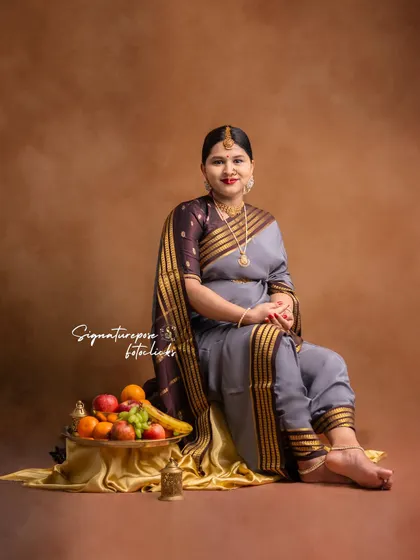 This seated portrait in a grey saree is simple yet elegant, with traditional props adding to the composition.
