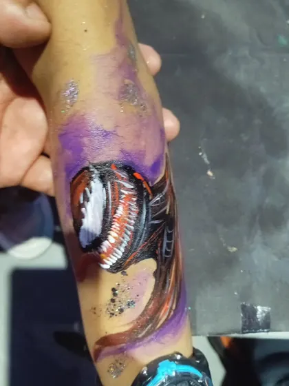 An arm painting of Venom, showing the character's head and part of its body. The purple background and glitter add an otherworldly feel.