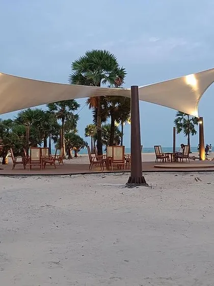 As dusk settles, this sculpted tensile roof on the beach is illuminated, creating a dramatic silhouette that echoes the gentle movement of the tides.