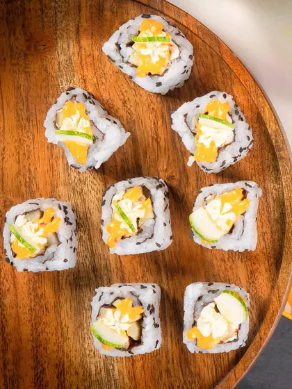 An overhead shot of the Cucumber Cream Cheese rolls scattered on a wooden platter.