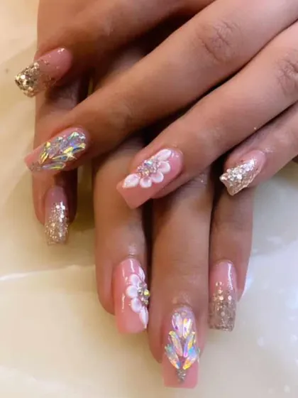 An incredibly detailed and luxurious set of pink extensions. It features 3D sculpted flowers, large iridescent crystals, and gold glitter accents for a truly show-stopping look.