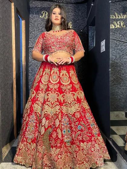 A full bridal look featuring a heavy red lehenga and a matching choker necklace, showcasing our complete rental solutions.
