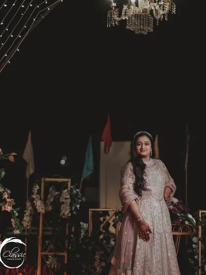 The bride, looking radiant against the backdrop of her Sangeet decor. The soft lighting and elegant floral arrangements are designed to make everyone look and feel their best.