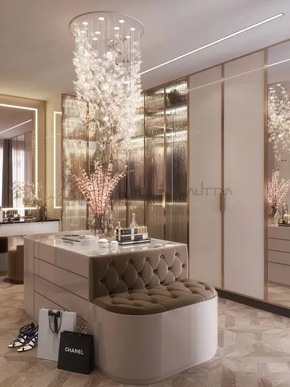Elegance and sophistication meet in this bespoke luxury dressing room. The design combines soft neutral tones, mirrored surfaces, and exquisite lighting, with a central island featuring a tufted seating area for a touch of comfort.