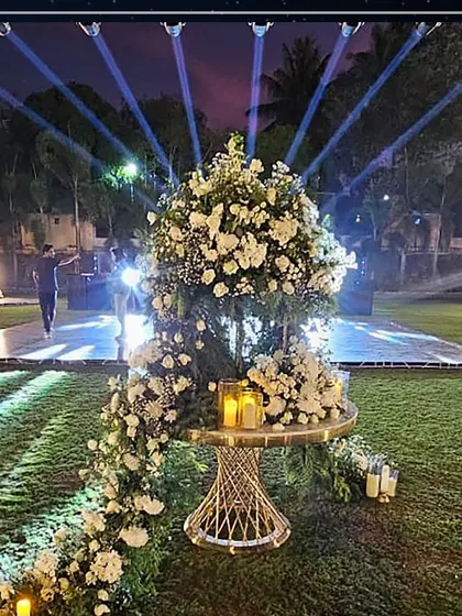 A dramatic floral centerpiece from the '40 Shades of Elegance' party. The cascading arrangement of white flowers was illuminated by spotlights, creating a stunning focal point in the outdoor lounge area.