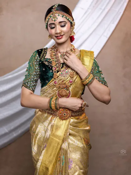 The elegance of a traditional bride. This golden Kanjeevaram saree paired with our custom green velvet blouse creates a look of pure opulence.