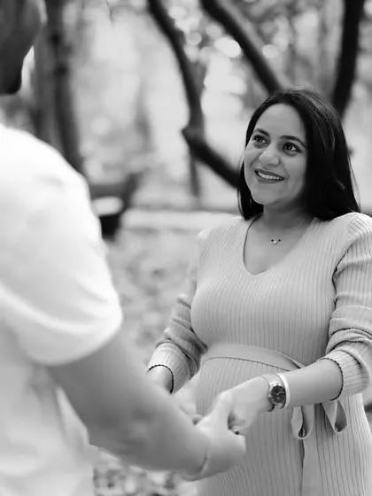 A black and white portrait focusing on her joyful expression as she holds her partner's hands. The image is full of light and happiness.