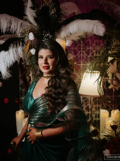 A moody, atmospheric shot from the reception. The lighting highlights her bold red lip and the intricate details of her outfit.