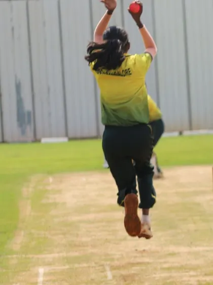 The peak of a bowler's action, captured from behind, showing the power generated.