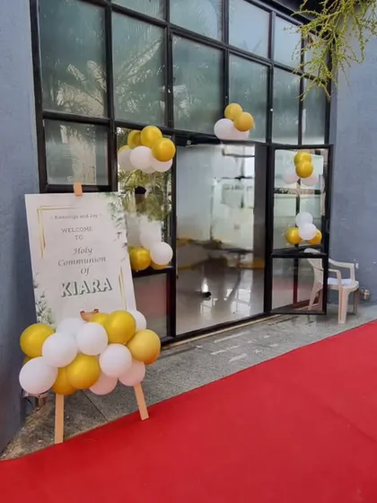 The entrance to a Holy Communion ceremony, with a personalized welcome sign and a simple white and gold balloon arrangement.
