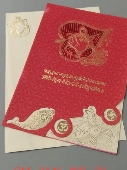 A bright red card featuring a large, stylized Ganesha in gold foil, along with other auspicious symbols. This is a bold and traditional choice for a Hindu wedding invitation.