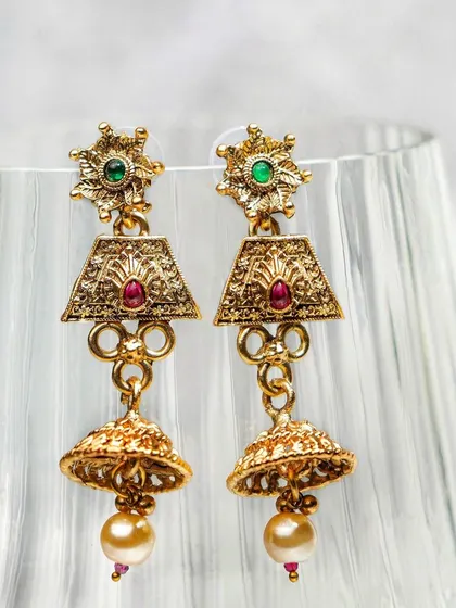 Traditional jhumka earrings styled against a fluted glass, using light and shadow to create an elegant mood. This creative approach elevates a standard product shot.