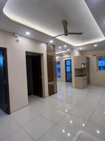 A spacious, unfurnished living area in a newly completed apartment. This image shows the false ceiling, lighting, and the partition that defines the entryway.