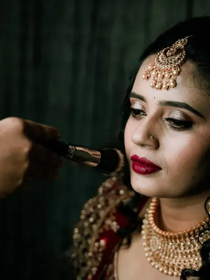 A close-up of a bride getting her makeup done, with a focus on her elegant look and jewelry.
