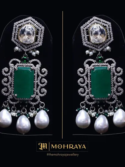 A pair of stunning designer earrings featuring large emeralds, uncut Polki, and pearl drops. These can be rented or bought to elevate any outfit.