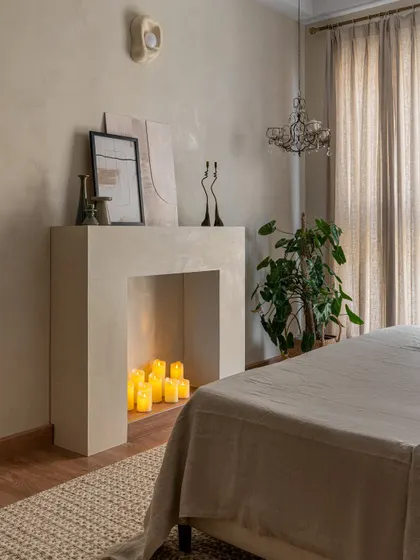 We love adding unexpected details. This bedroom features a minimalist faux fireplace filled with candles, creating a cozy and romantic focal point without the need for a real chimney.