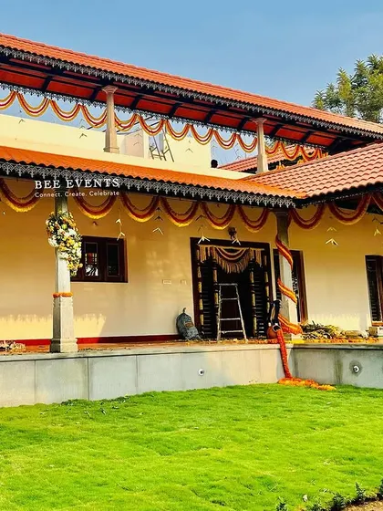 A full view of a traditional farmhouse decorated for a housewarming ceremony. The marigold garlands tracing the roofline give the home a classic and celebratory look.