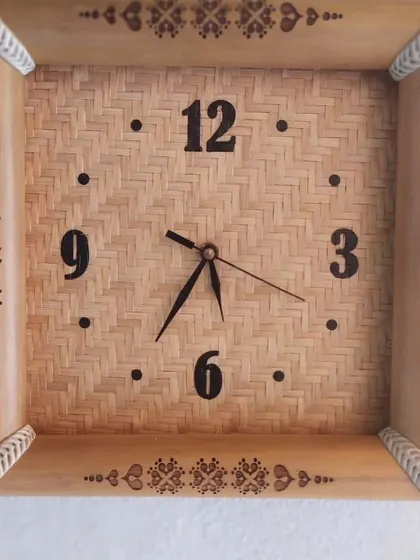 This handcrafted bamboo wall clock features a woven face and an intricately decorated frame. It's a functional piece of art that brings a touch of natural elegance and traditional design to your wall.