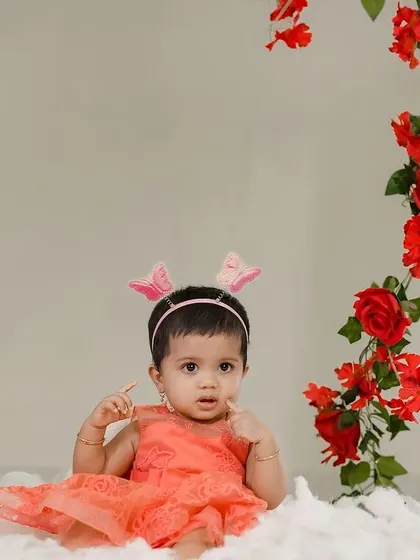 A curious baby girl surrounded by a frame of red roses. We love creating these beautiful and artistic studio portraits.