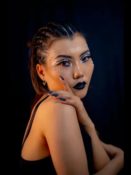 A close-up on a creative catwalk look, highlighting the precise application of facial gems and the sharp, graphic eyeliner. These details are crucial for high-fashion and editorial makeup.