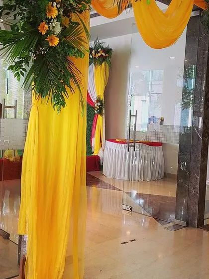 A simple floral entrance arch with yellow drapes and fresh flower bouquets. This type of decor is versatile and can be used for various events like housewarmings, engagements, or festival gatherings.