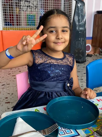 Peace and smiles from a happy party guest at the dining table.