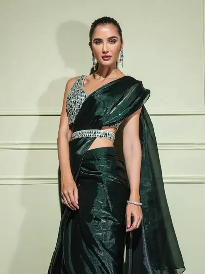 This emerald green organza saree has a beautiful metallic sheen. It's paired with a sequined blouse and a delicate, embellished belt to cinch the waist.