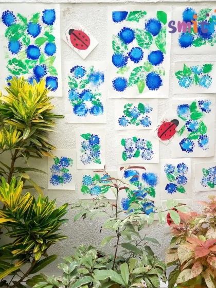 The finished hydrangea paintings, adorned with sponge-printed ladybugs, are displayed in our garden. We proudly showcase the children's beautiful artwork.