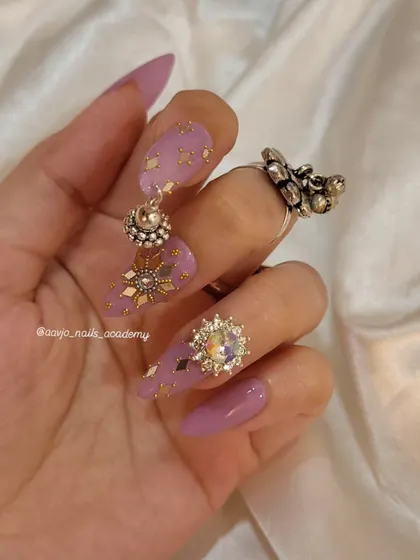Another angle of the purple and gold Navratri nails, showing off the large crystal charm and the delicate placement of the gold accents.