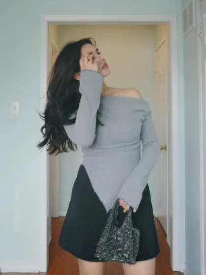A chic outfit featuring a grey asymmetrical top and a black skirt.