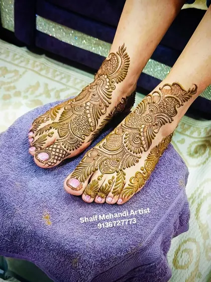 A side view of a heavy bridal foot mehandi, featuring peacock and paisley motifs that cover the entire top of the foot.