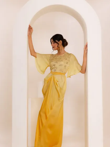 Another look from the A.Projekt campaign, this time a draped yellow midi dress. The styling against the arched, minimalist set was designed to highlight the garment's modern silhouette and delicate embroidery.