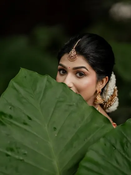 A beautiful bridal portrait framed by lush green leaves. This creative composition adds an artistic and natural touch to the image.