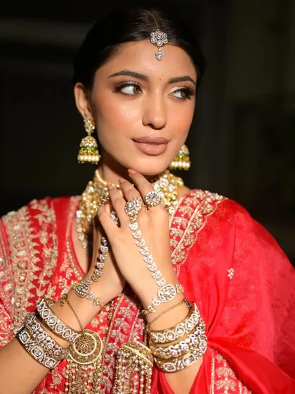 A close-up on the hands and jewelry, showing how every detail of the look is coordinated. The makeup is soft and complements the intricate details.