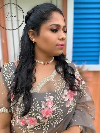 This is a lovely makeup style for a pre-wedding photoshoot. The look is soft and romantic, with pink tones on the eyes and lips that complement the floral embroidery on the sheer grey saree.