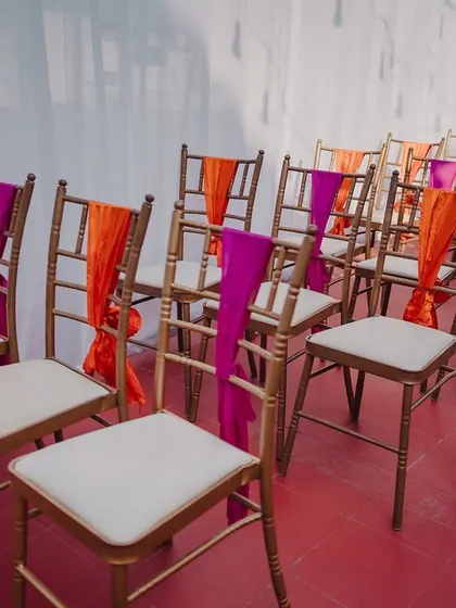 Guest chairs decorated with orange and pink drapes.