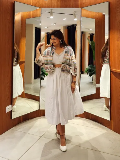This pose highlights the movement and layering of the embellished jacket over the white co-ord set.