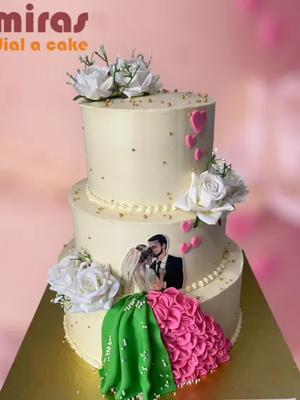 An elegant three-tier engagement cake with a personal touch. The cake features an edible photo of the couple and a beautiful ruffled dress detail made of frosting.