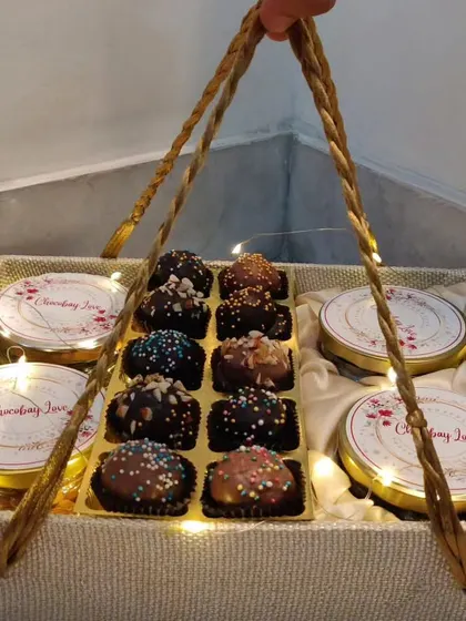 A still image of the indulgent chocolate truffle and jar hamper. The golden carry handles make it easy to present, and the lights add a festive sparkle.