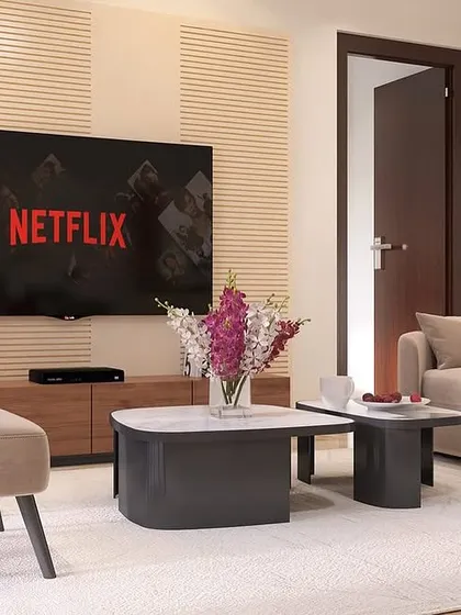 This living room design focuses on minimalist principles. The clean lines of the TV unit, the simple forms of the sofa and accent chair, and the neutral color palette create a calm and uncluttered environment.
