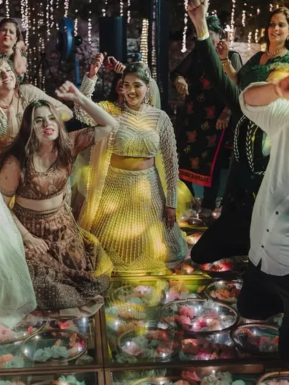 Guests enjoying themselves on a unique glass-lit dance floor filled with flowers, adding an extra layer of magic to the sangeet night.
