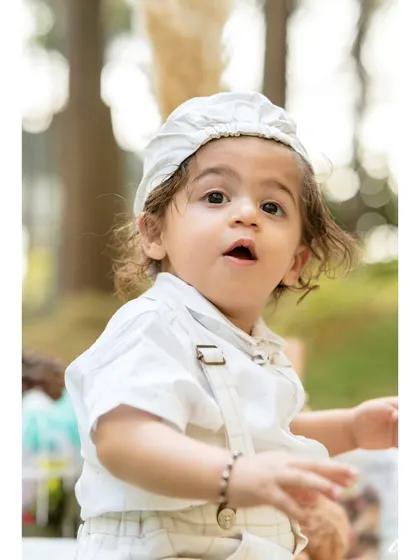 A sweet, curious expression captured in a close-up portrait. This little boy, part of a twin duo, looks on with wide-eyed wonder during his outdoor pre-birthday session.
