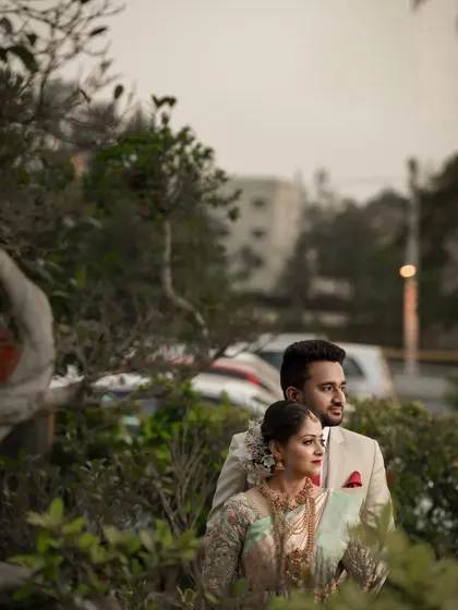 A candid shot of a couple looking into the distance, captured in a garden setting during their reception. This photo has a thoughtful, cinematic quality.