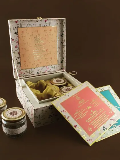This floral invitation box opens to reveal a satin-lined interior with compartments for multiple gift jars, combining beauty with functionality.