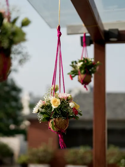 Hanging floral arrangements in coconut shells, a creative and sustainable decor idea for a tropical or rustic themed wedding.