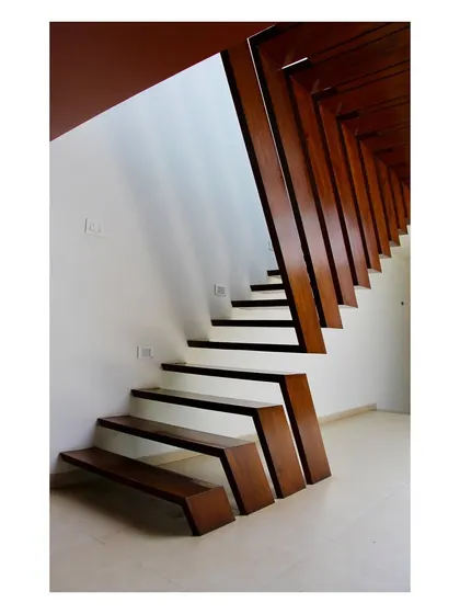 The unique, angular design of the staircase in the 'Boxed In House', crafted from recycled teakwood. The folded form is both a functional circulation element and a powerful sculptural statement that defines the character of the interior.