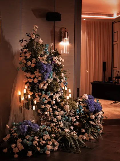 We make grand entrances. This stunning floral installation, overflowing with white, blue, and purple hydrangeas and roses, and dotted with glowing candles, set a luxurious and enchanting tone for a 50th birthday celebration from the moment guests arrived.