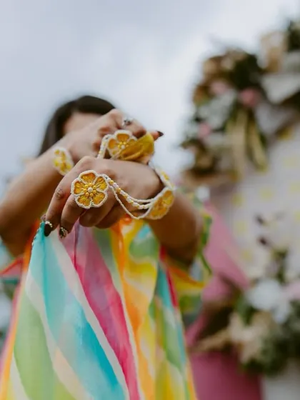 A close-up on the bride's hands, showing off her beautiful floral jewelry during a Mehendi or Haldi ceremony.