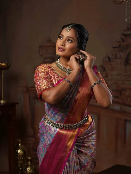 This pose highlights the traditional jewellery and the soft, elegant hairstyle that completes this South Indian look.