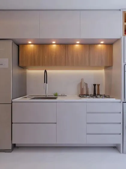 A compact and efficient kitchen layout. This design features handle-less cabinets, a combination of wood and white finishes, and smart placement of the sink and cooktop to maximize a smaller space.